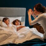 a woman story telling with two children in bed